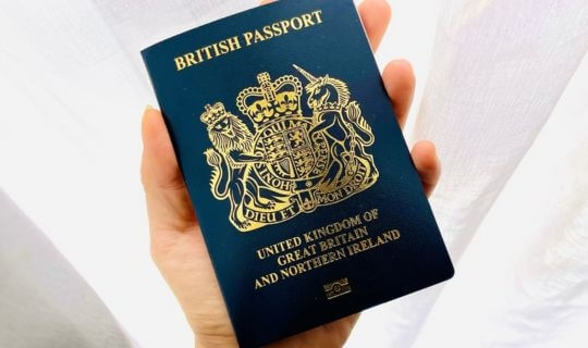 A hand holding a new Navy British citizen passport.