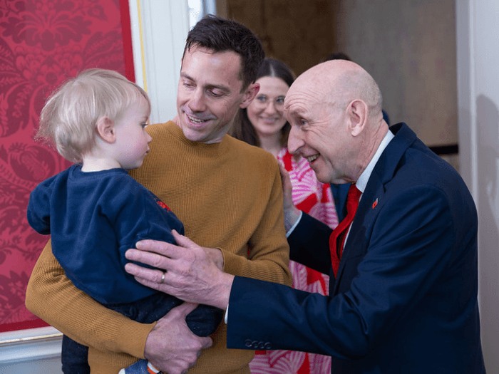 Chancellor of the Exchequer, John Healey, greets a father holding his young son.