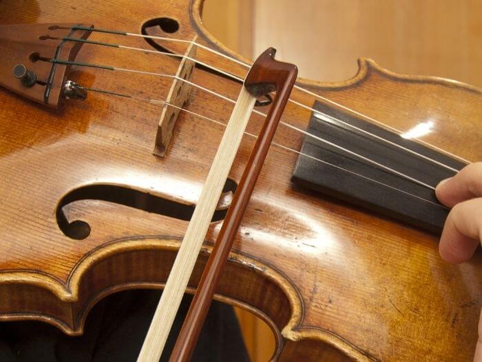 Close up of hand on bow playing violin.