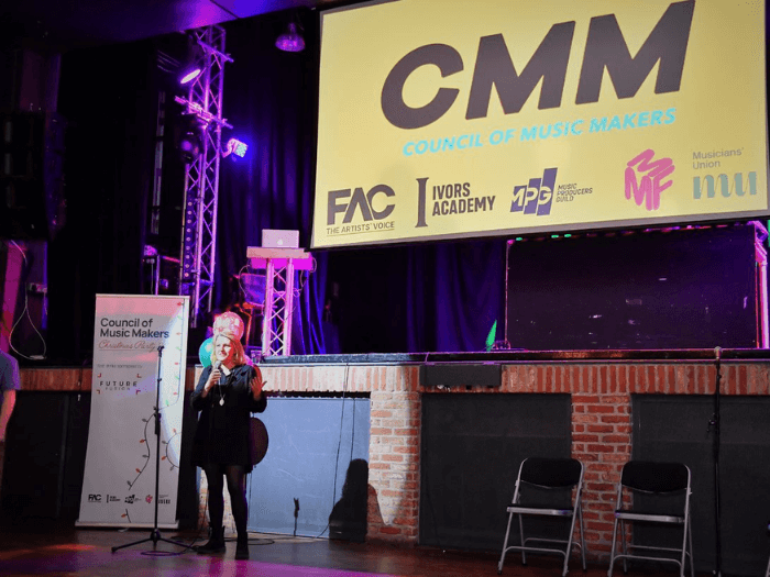 General Secretary Naomi Pohl on stage in front of a CMM banner.