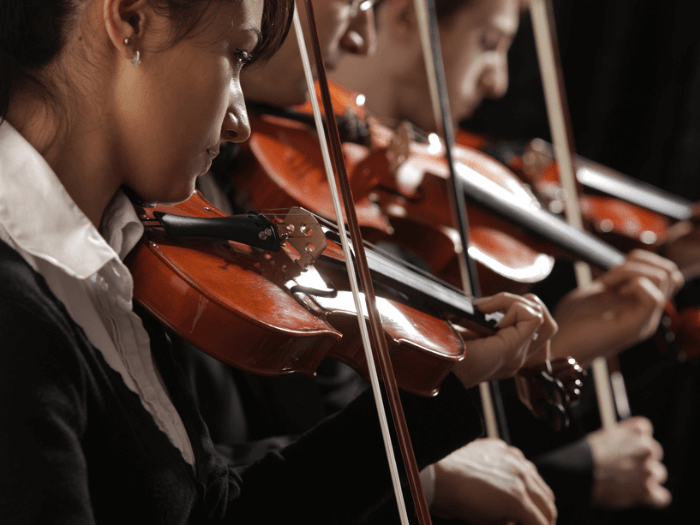 Three violinists as part of a symphony orchestra.