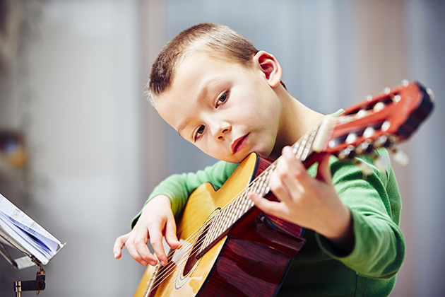 Photograph of child playing guitar.