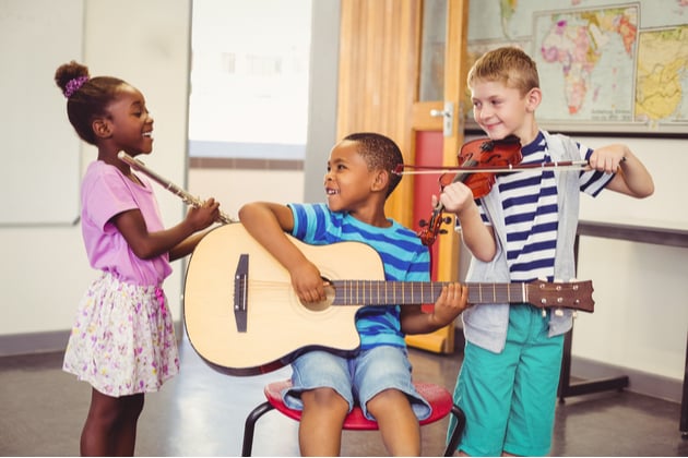 Photograph of a group of children playing music in a classroom.