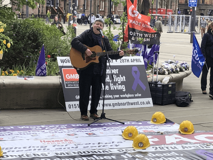 Claire performing with an acoustic guitar on International Workers’ Day in 2022 in Manchester.