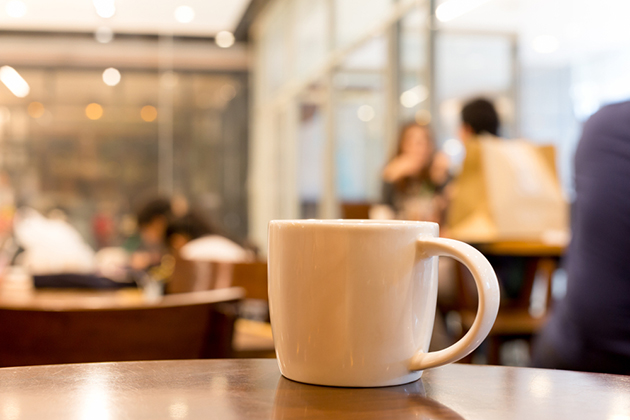 Photograph of a coffee cup with a blurred background of a coffee shop