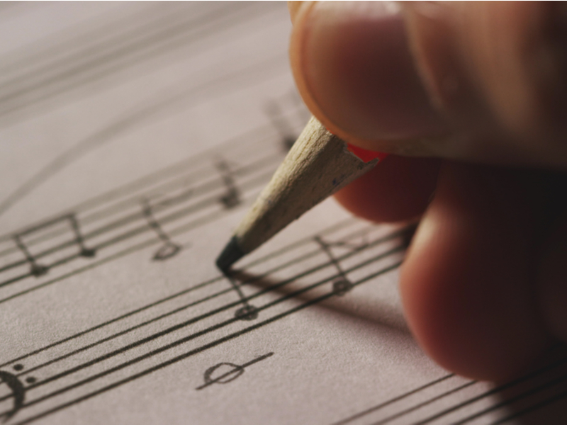 Close up of hand writing musical notes on paper