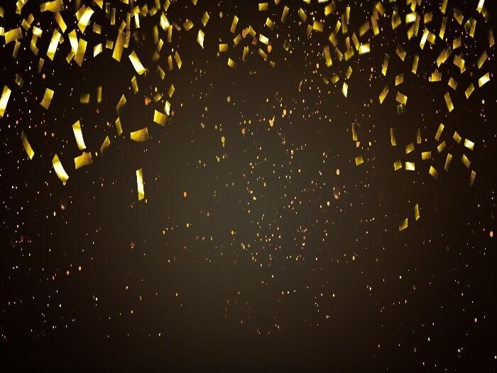 Black background with golden glitter and confetti to represent a celebration.