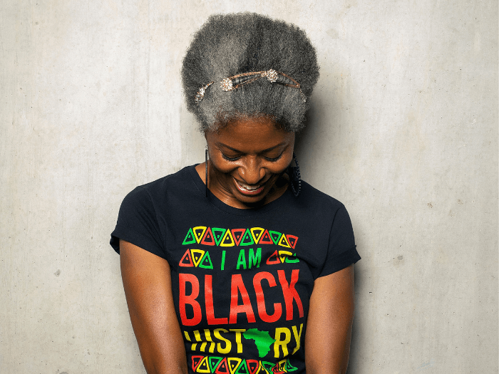 Photo of DJ Paulette, smiling downwards in a t-shirt that reads 