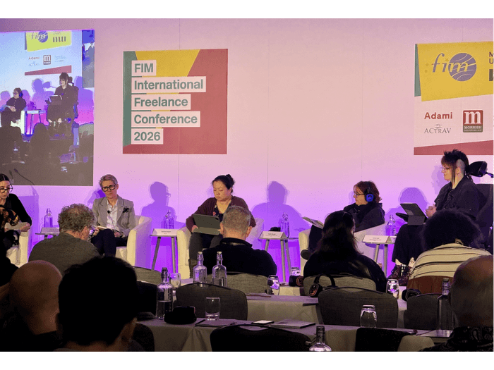 The five panellists sat on stage, in purple lighting, with FIM logo behind them.
