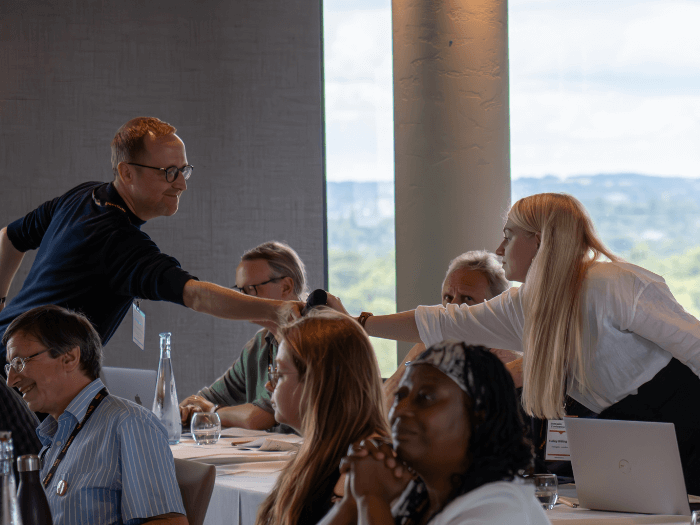 MU Head of Education and Wellbeing, Chris Walters, passing a microphone to a young member to speak about their motion at the last Delegate Conference in 2023.