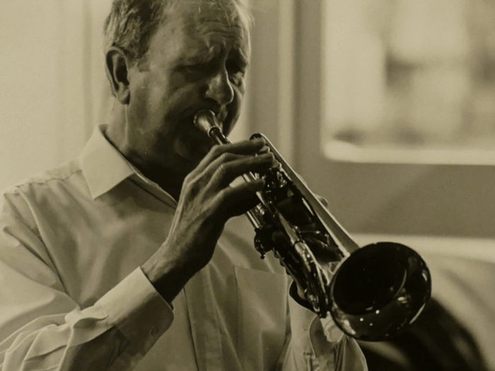 Sepia photo of Derek playing trumpet.
