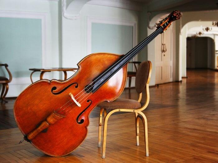 Double bass leaning against a wooden chair.