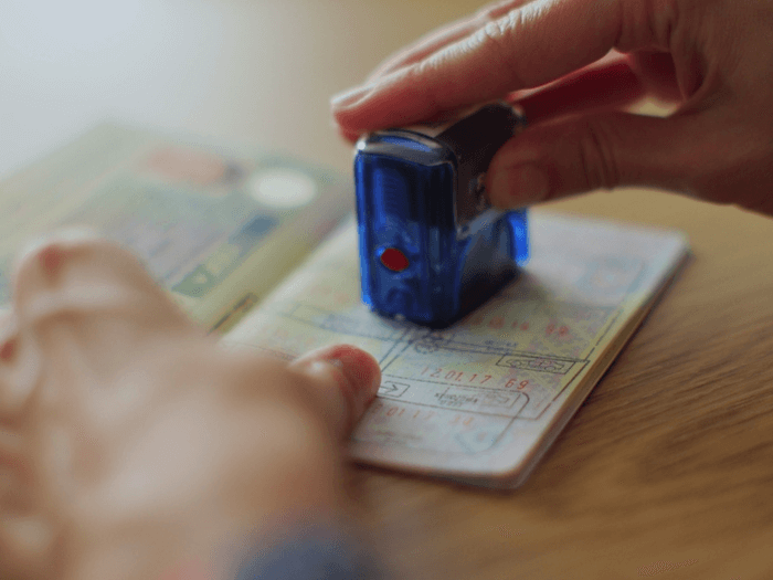 A hand stamping a passport at border control.