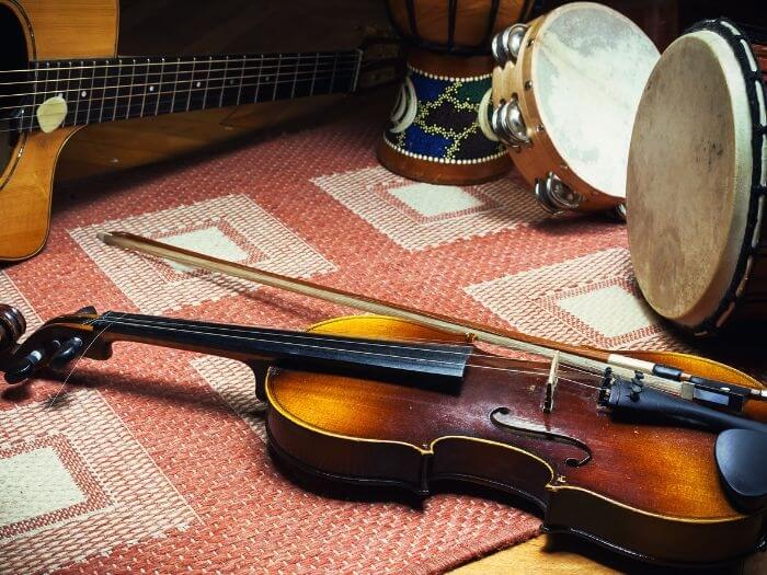 Violin, acoustic guitar and percussion instruments on tiled carpet representing European folk style.