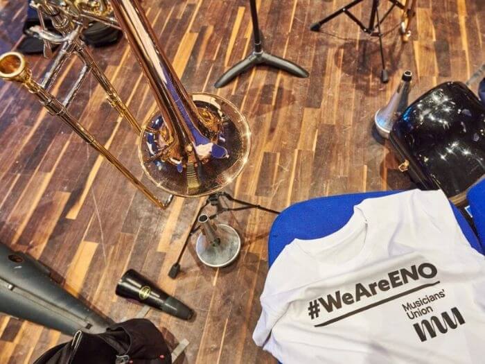 A t-shirt saying #weareeno draped over instruments in a empty orchestra.