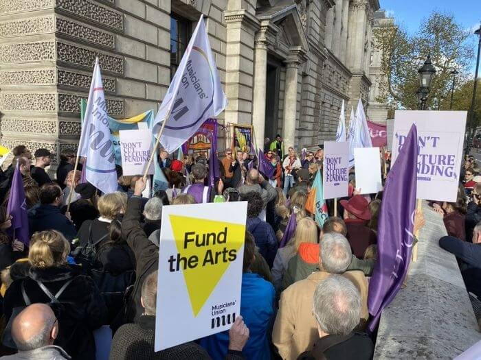 People at the ENO joint Unions demo from November 2022 holding signs reading Fund the Arts.