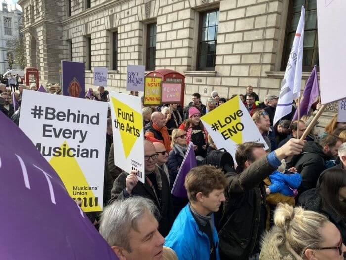People at the ENO joint Unions demo from November 2022 holding signs reading #Behindeverymusician and #LoveENO