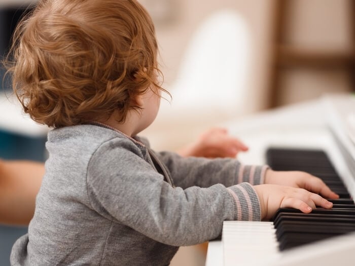 Toddler with hands over a piano.