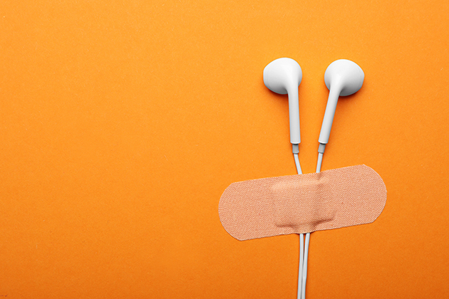 Photograph of a earbud earphones stuck to a bright background with a first-aid style sticking plaster