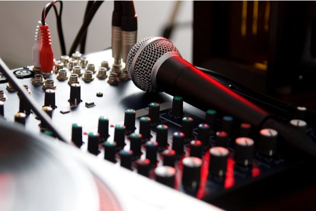 Close up of mixing desk with microphone placed on top, cast in red light.
