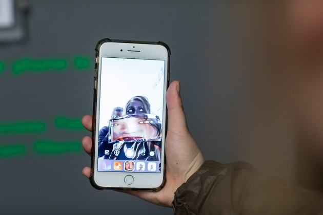 Phone screen displaying art work, held by a hand.