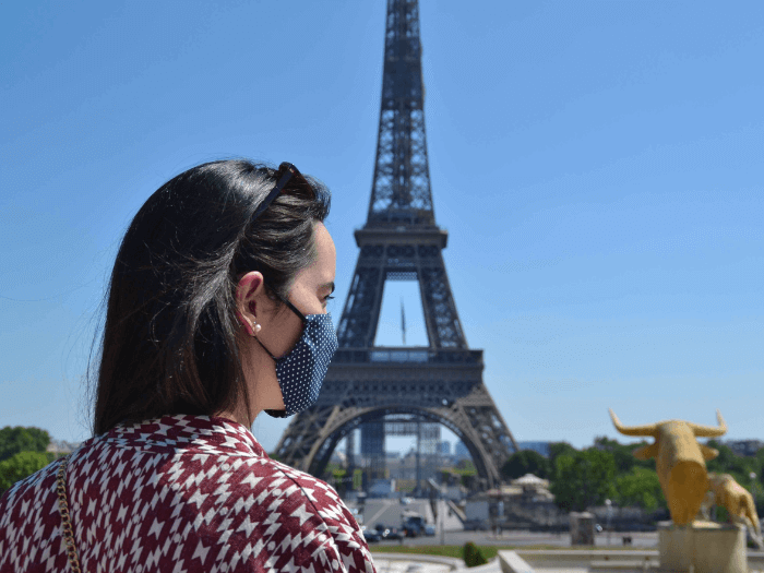 Young French woman with a cloth face mask photographed in front of the Eiffel Tower in Paris, France, during the Coronavirus pandemic..