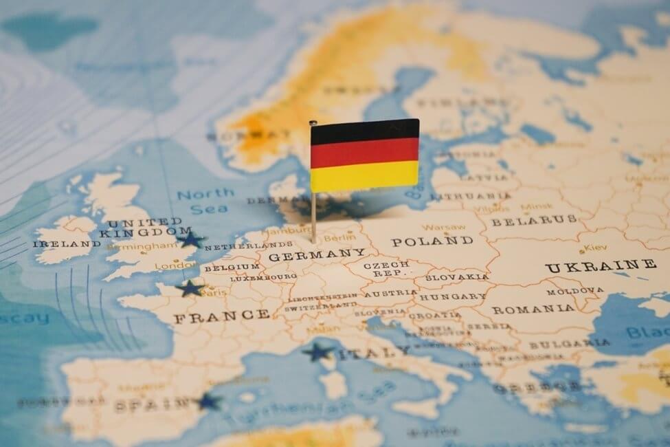 Close up of a world map with a small German flag pinned into Germany.