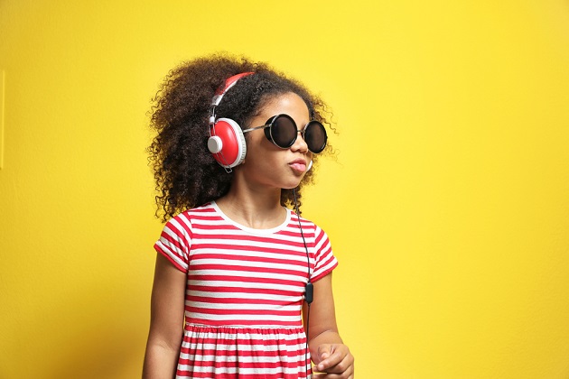 Photograph of little girls with earphones and sunglasses on sunshine yellow background