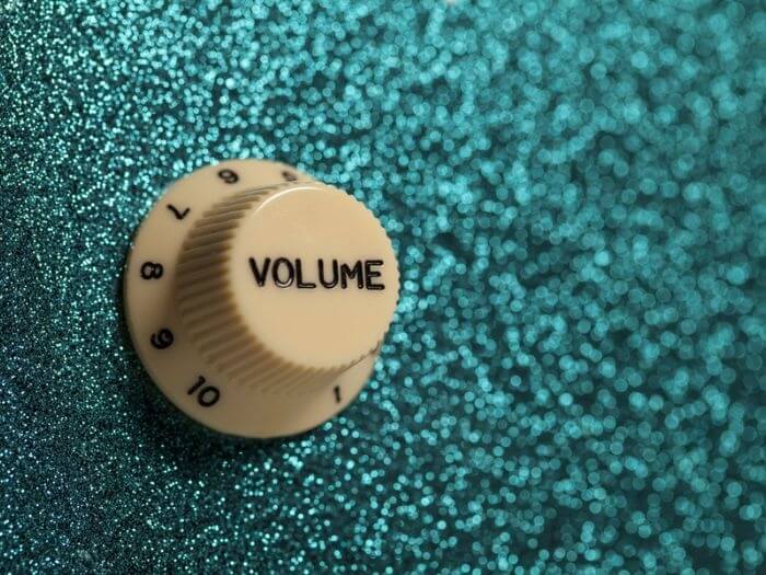 Volume dial against a glittery green background.