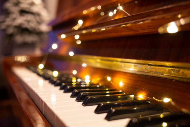 Photograph of a piano keyboard with warm fairy lights spread out across the keys.