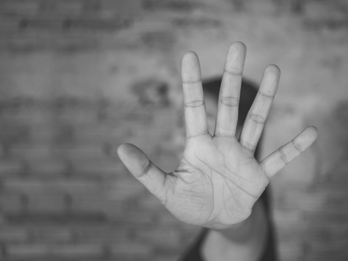 Black and white image of outstretched hand, representing no and harassment.