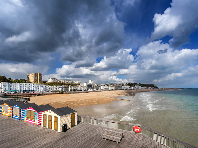 Photograph of an empty Hastings Pier, with a stormy sky in the background.