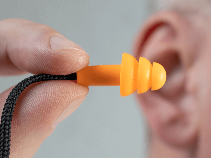 Silicone orange ear plugs with string on white background.