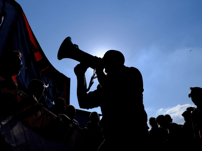 A silhouette of a man speaking into a megaphone as part of a trade union protest.