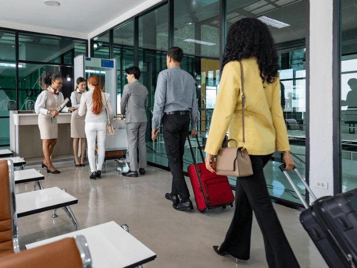 A line of passengers in an airport queuing to go through a security scanner.