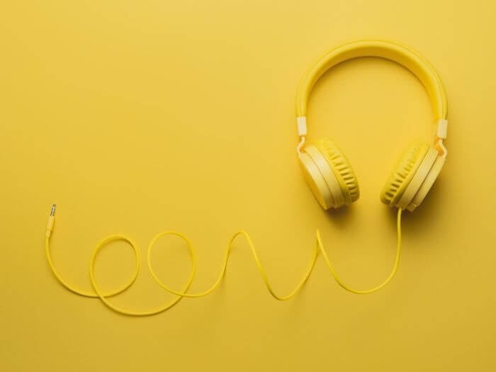 Yellow headphones on yellow background. Listening concept.