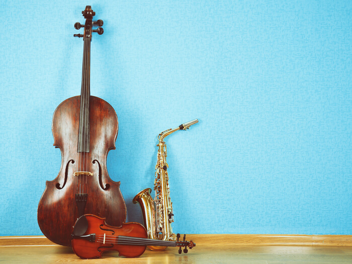 Cello, violin and saxophone against a bright blue background.