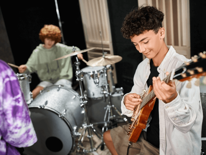 Two young male musicians playing guitar and drums in a band.