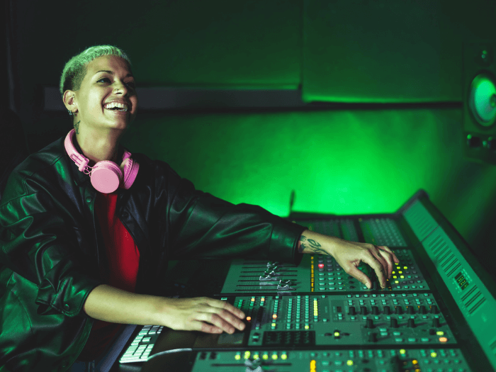 Female audio engineer at mixing desk in studio.