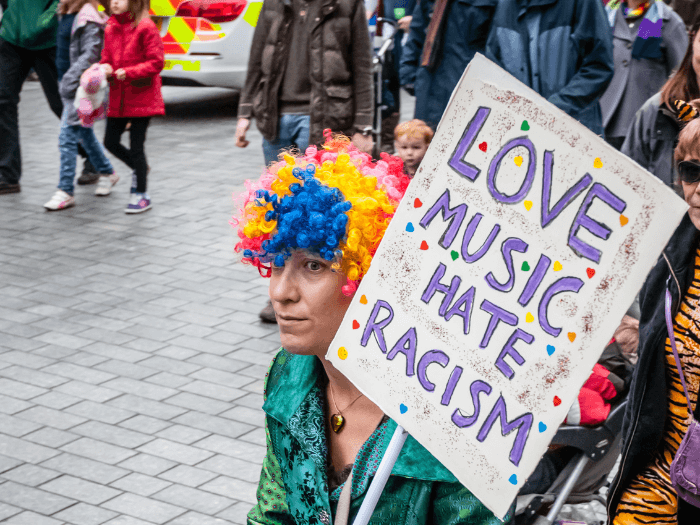 An activist holding a Love Music Hate Racism sign as part of a protest in the UK.