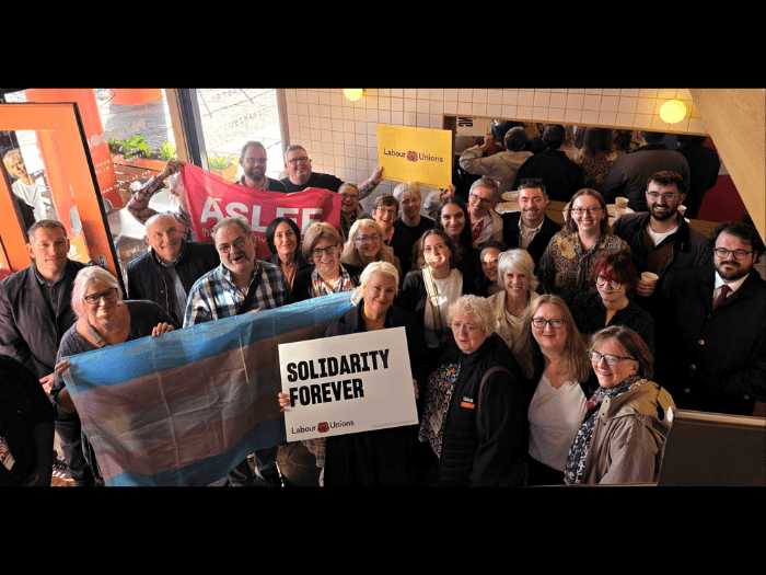 A big group of people from various unions holding up flags and placards with 'Labour Unions' and 'Solidarity Forever'