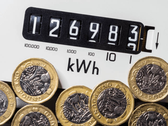 Electricity meter with one pound coins in front. Concept for energy supplier, high bills, price rise, cost of living, inflation and fuel poverty.