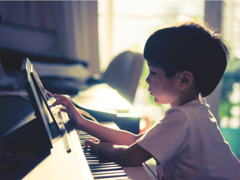 Photograph of a small boy playing the keyboard at home.