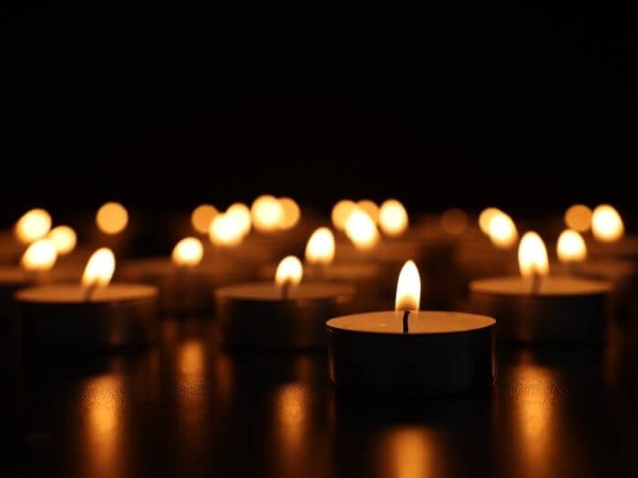 Close up of burning tea lights against a dark background.