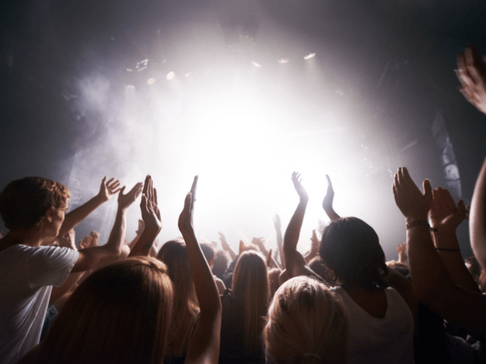 View of a stage lit up in white light, from the perspective of a crowd looking up.