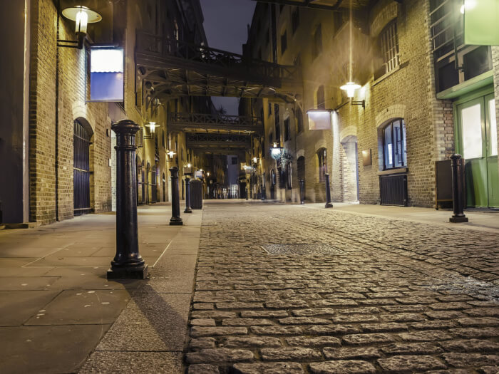 A well lit but very empty street in London at night time.