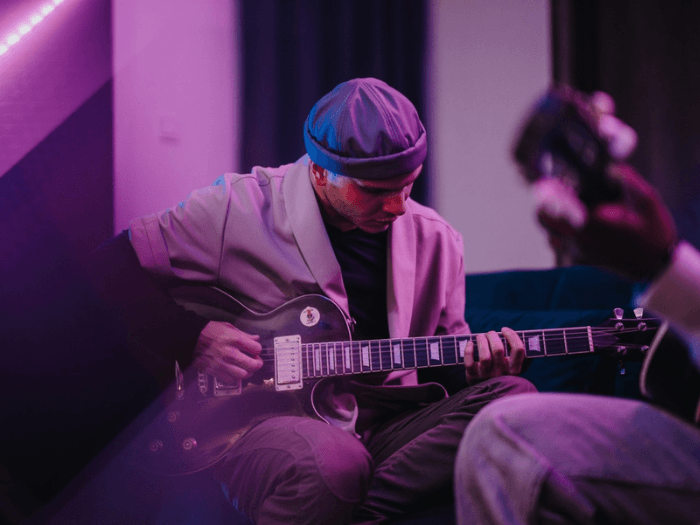 A musician sitting down playing electric guitar on stage.