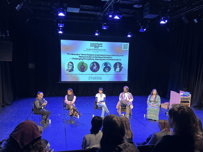 Diljeet, sat on stage with the panellists, speaking into a microphone.