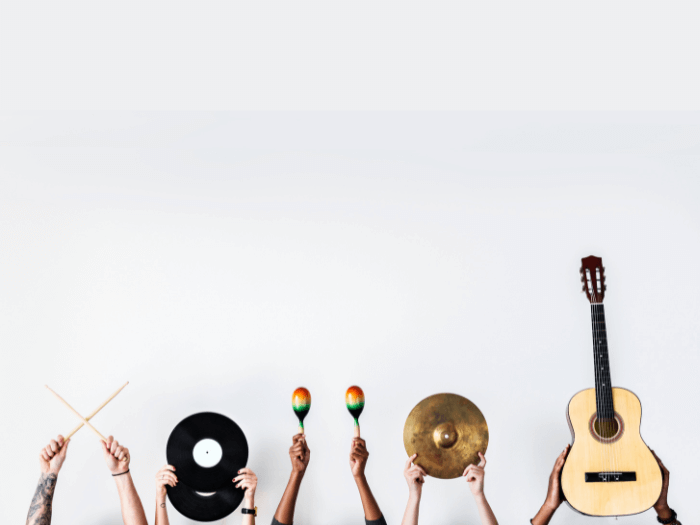 Hands holding musical instruments. Left to right, drum sticks, record, maracas, symbol and acoustic guitar.