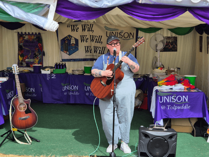 Maddy Morris performing on guitar at Tolpuddle 2025.